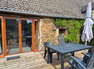 a table and chairs on a wooden deck with an umbrella at Gîte Marie, Beynat, Corrèze in Beynat