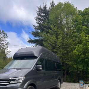 a black van is parked in a parking lot at Góry Stołowe Camp - Rodzinne pole biwakowe, Kampery, Przyczepy, Namioty in Radków