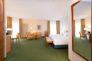 a hotel room with a bed and a living room at Dorint Charlottenhof Halle (Saale) in Halle an der Saale +58 photos