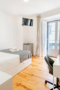 a white bedroom with a bed and a desk and a chair at Suites - Elevador da Bica in Lisbon