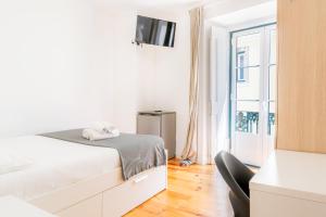 a white bedroom with a bed and a window at Suites - Elevador da Bica in Lisbon