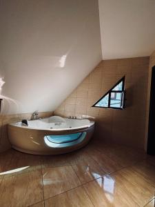 a large bath tub in a room with a window at Vila Antanta Podu' Cu Lanturi in Bacău