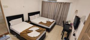 a small room with two beds and a television at Tanjong Boutique Hotel in TanjongMalim