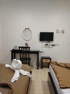 a room with two beds and a desk with a towel at Tanjong Boutique Hotel in TanjongMalim +3 photos