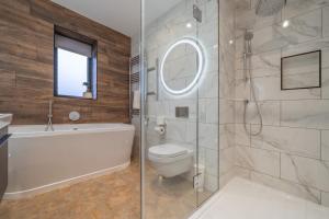 a bathroom with a tub and a toilet and a sink at Parklands in Penrith +33 photos