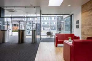 an office lobby with red furniture and glass doors at Fitzroy Court near Luton Airport in Luton