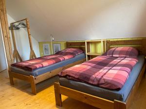 two beds in a room with wooden floors at Ferienhaus Wehretal - auf separatem Grundstück in Langenhain