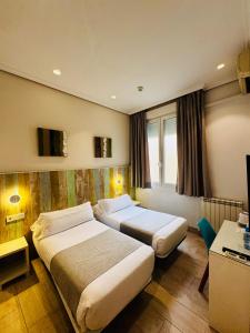 a hotel room with two beds and a television at Hostal Cervelo in Madrid