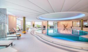 a pool in a hotel lobby with a swimming pool at Hotel VierJahreszeiten am Seilersee in Iserlohn