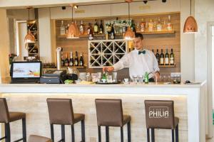 a man standing behind a bar in a restaurant at Philia Hotel in Podgorica