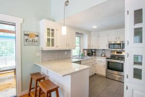 a kitchen with white cabinets and a counter with stools at Private Pool Large Deck and Game Room in Dennis