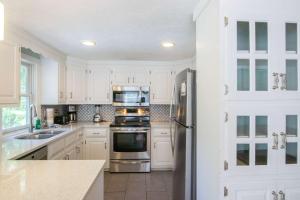a kitchen with white cabinets and a stainless steel refrigerator at Private Pool Large Deck and Game Room in Dennis