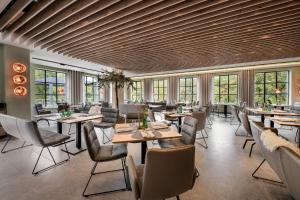 a restaurant with tables and chairs and windows at Hotel VierJahreszeiten am Seilersee in Iserlohn