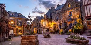 a courtyard of an old building with flowers in front of it at Gîte du Vieux Moulin in Rochefort