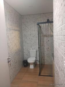 a bathroom with a toilet and a glass shower stall at Casa Magalhães Hospedaria in Extrema