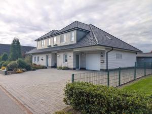 a white house with a black roof and a driveway at Ferienwohnung Witte Huus, 15212 in Leer