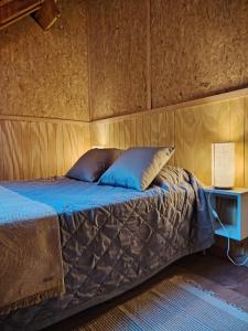 a bed in a room with a wooden wall at Bosque Hostel in Villa Traful +26 photos