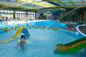 a child sliding down a slide in a swimming pool at Camping 5 étoiles - Parc aquatique - eecdae in Saint-Jean-dʼOrbetiers