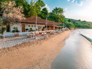 a beach with tables and chairs and a building at Thracian Cliffs Golf & Beach Resort in Kavarna