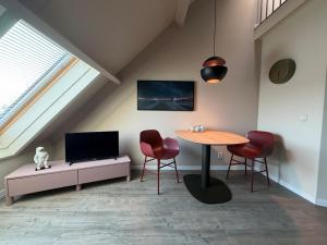 a living room with a table and chairs and a tv at Appartementenhotel Tjermelân Terschelling in Oosterend