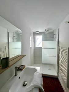 ein weißes Badezimmer mit Waschbecken und Spiegel in der Unterkunft Le Conki ( Parking gratuit ) in Chartres