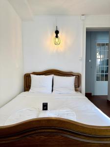 ein großes Bett mit Holzrahmen und weißer Bettwäsche in der Unterkunft Le Conki ( Parking gratuit ) in Chartres