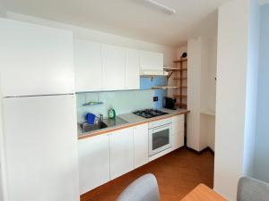 a kitchen with white cabinets and a refrigerator at Meduse Seafront - Attico al Mare in Torvaianica