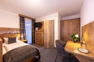 a hotel room with a bed and a desk at Hotel AlpinaRos in Berchtesgaden