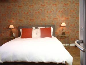 a bedroom with a white bed with red pillows at Le Cosy Nid in Leyme