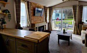 a kitchen and living room with a fireplace and a couch at Cheviot Pines Northumberland in Swarland