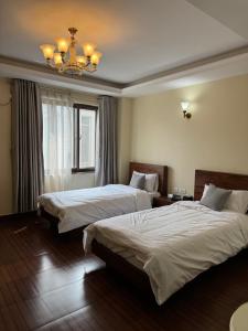a hotel room with two beds and a chandelier at Tashi Tagay Hotel & Apartment in Kathmandu