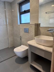 a bathroom with a toilet and a sink and a window at Tashi Tagay Hotel & Apartment in Kathmandu +39 photos