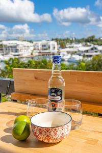 a bottle of alcohol and two glasses and a bowl on a table at Duplex mezzannine vue marina in Le Gosier