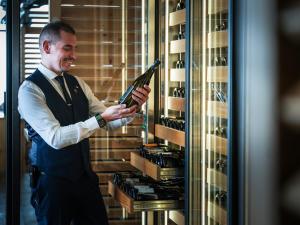a man in a tuxedo standing in front of a wine rack at Hôtel Koh-I Nor by Les Etincelles in Val Thorens +85 photos