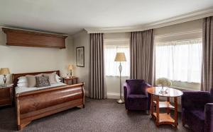 a hotel room with a bed and a table and chairs at Brandshatch Place Hotel & Spa in Dartford