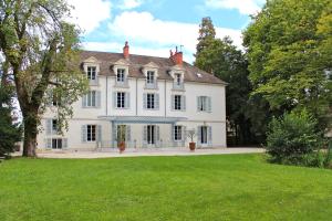 une grande maison blanche avec une pelouse verte dans l'établissement Château de tailly, à Meursault