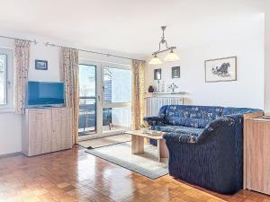a living room with a blue couch and a television at Apartment Alpenseeblick by Interhome in Seebruck