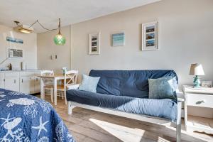 a living room with a blue couch and a kitchen at Steps to Sandy Beach! Oceanfront Old Orchard Gem in Old Orchard Beach