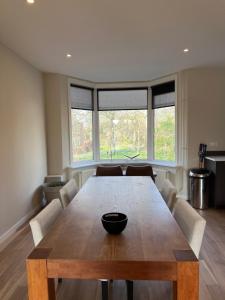 a dining room with a wooden table and two windows at Nette maisonnette in groene rustige wijk in Rijswijk