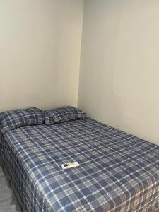 a bed in a room with a blue plaid at Meu cantinho 5 in Santarém