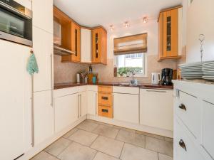 a kitchen with white cabinets and a window at Holiday Home Noordwijk near Beach & Sauna in Noordwijk