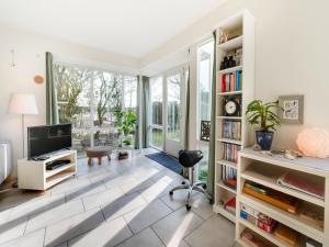 a living room with a television and bookshelves at Holiday Home Noordwijk near Beach & Sauna in Noordwijk