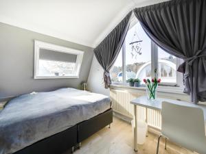 a bedroom with a bed and a table and windows at Holiday Home Noordwijk near Beach & Sauna in Noordwijk
