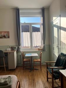 a living room with a table and a window at Coquelicot in Armentières