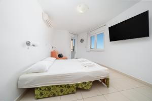 a white bedroom with a large bed and a flat screen tv at Villa Juric 2 in Baška Voda