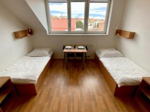 two beds in a room with a table and a window at TWILL Apartments in Brno