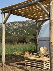 a wooden pergola with a table and a chair at Les Dômes du Moulin in Urtaca