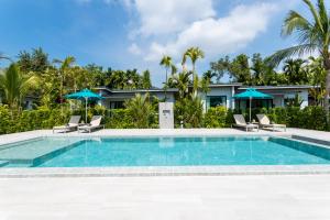 a pool with chairs and umbrellas in front of a house at Nanuea Village Ao Nang in Ao Nang Beach