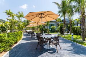 a patio with tables and chairs with umbrellas at Nanuea Village Ao Nang in Ao Nang Beach