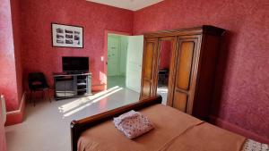 a bedroom with red walls and a bed and a television at La Chaussée de l'Etang in Marcenay +11 photos